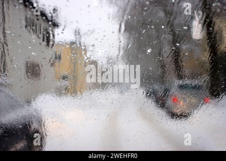 Verschwommener Blick durch die nasse Windschutzscheibe eines Autos im Winter bei Schneefall Stockfoto