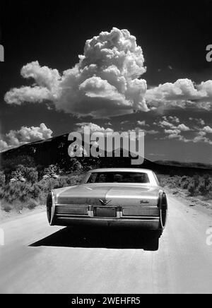 1968 Cadillac Sedan Deville auf einer unbefestigten Straße im City of Rocks National Reserve in Idaho, mit großer weißer Wolke, USA Stockfoto