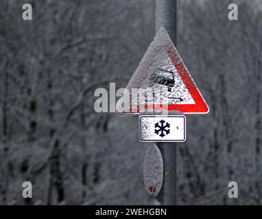 Ein deutsches Verkehrszeichen Vorsicht Gefahr des Schleuderns bei winterlichem Schneefall, beleuchtet durch den Kamerablitz Stockfoto
