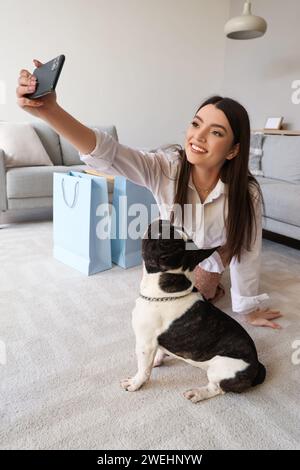 Junge Frau mit ihrer französischen Bulldogge, die zu Hause Selfie macht Stockfoto