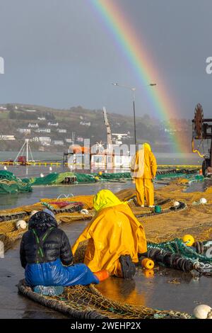 Fischer reparieren Netze unter einem Regenbogen in Union Hall, West Cork, Irland. Stockfoto