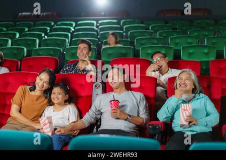 Asiatische Eltern und ihr Kind sehen sich gerne einen Film an, genießen Popcorn zusammen im Kino, gemeinsames Lachen, Binden und die einfachen Freuden eines D Stockfoto