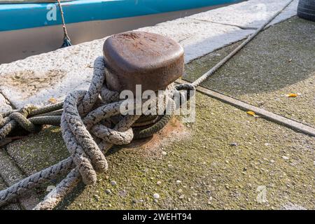 Nahaufnahme eines Knotens, der mit einem Fischerbootsseil gemacht wurde, das an einem eisernen Haken in einem Hafen in Grado, Italien, verankert ist. Artikel für Fischerboote. Marineartikel. Stockfoto