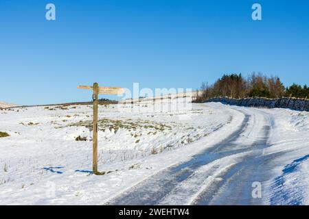 Ein Wegweiser in den Yorkshire Dales in England an einem wunderschönen winterlichen Tag mit viel Schnee auf dem Boden und klarem blauem Himmel. Auf den drei Gipfeln. Stockfoto