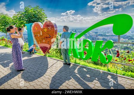 Die Leute machen Fotos am Schild „I love Kok Tobe“ im Kok Tobe Park, Almaty Kasachstan. Stockfoto