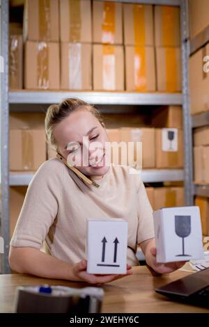 Frau, die ein Mobiltelefon oder Tablet verwendet, um mit Kunden zu kommunizieren. Lieferung von Waren über private Kurierdienste. Konzepte des Online-Verkaufs und weiter Stockfoto