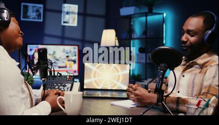 Eine weibliche Radiosenderin hat ein Live-Gespräch mit einem Mann und nimmt Diskussionen auf, damit das Publikum live zuhört. Influencer, der sich mit Journalisten unterhalten und Diskussionen für Fans zu Hause ausstrahlt Stockfoto