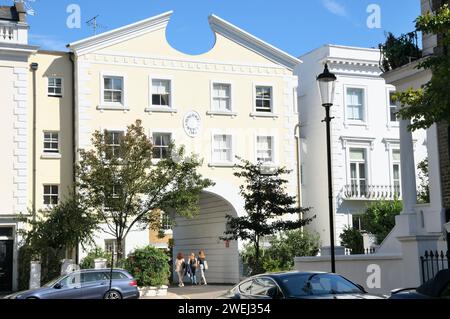 Drei junge Frauen gehen durch den Eingangsbogen der Sackgasse Pencombe Mews, Notting Hill, Kensington und Chelsea, West London, W11, England Großbritannien Stockfoto