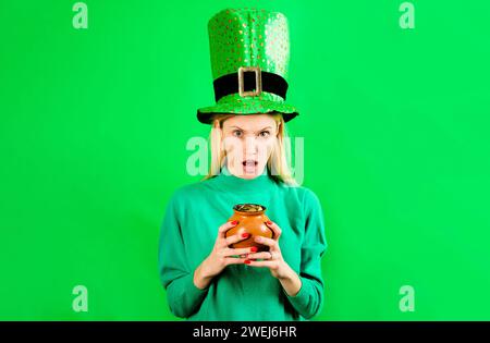 Patricks Tagesmädchen in Leprechaun Hut mit Topf Gold. Patrick's Day fest. Überraschte junge Frau in grünem Pullover und Hut. Tradition von Stockfoto