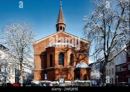 Die kölner ehrenfeld friedenskirche in der Rothehausstraße nach Schneefall vor blauem Himmel im januar 2024 Stockfoto