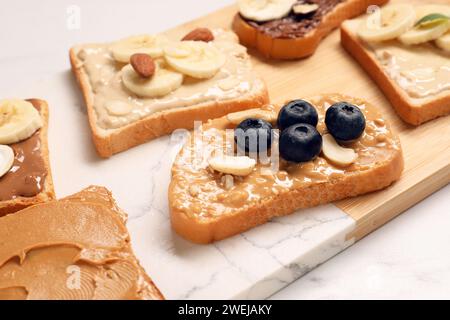 Toasts mit verschiedenen Nussbutter, Früchten und Nüssen auf weißem Tisch, Nahaufnahme Stockfoto