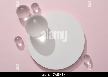 Weißes rundes Podium mit Glaskugeln auf pastellrosa Hintergrund. Standfuß für Modellpräsentationen von Kosmetikprodukten und Verpackungen Stockfoto