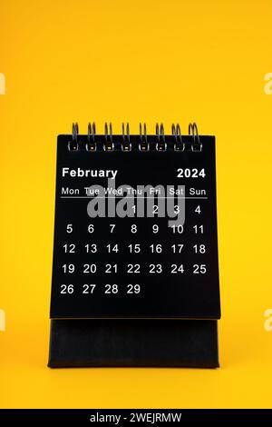 Schwarzer Kalender für Februar 2024. Desktop-Kalender auf gelbem Hintergrund. Stockfoto