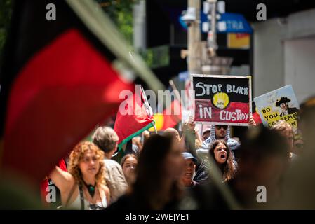 26. Januar 2024, Melbourne, Australien. Ein Demonstrant hält ein Schild mit der Aufschrift „Stop Black Death in Haft“, während sie mit etwa 30.000 anderen Demonstranten marschieren, die sich gegen den Australia Day oder Invasion Day versammelten. Quelle: Jay Kogler/Alamy Live News Stockfoto