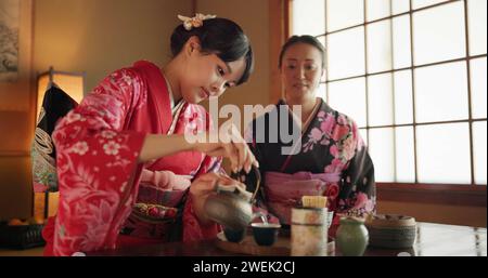 Japaner, Freunde oder Kimono für eine Teezeremonie in Chashitsu mit Frieden oder Tradition. Damen, temae oder Vintage-Kleid oder Gespräch mit Stockfoto