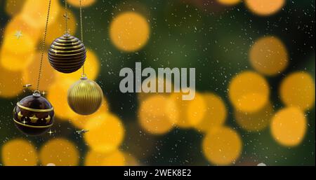 Schwingende schwarze und goldene weihnachtskugeln, fallender Schnee und orangene Bokeh-Lichter auf dunklem Hintergrund Stockfoto