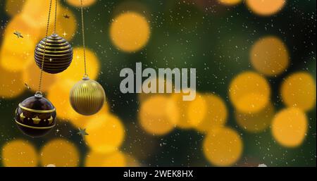Schwingende schwarze und goldene weihnachtskugeln, fallender Schnee und orangene Bokeh-Lichter auf dunklem Hintergrund Stockfoto
