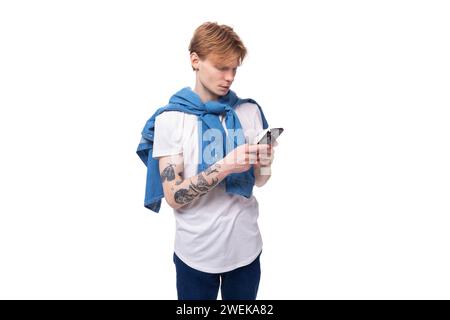 Junger, emotional schöner, schlanker, rothaariger Mann mit einem Tattoo auf den Armen ist in einem stilvollen blauen Hemd gekleidet. Stockfoto