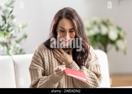 Eine überraschte junge Frau erhielt einen Liebesbrief von ihrem Freund und ein Verlobungsring war darin eingeschlossen. Stockfoto