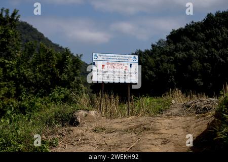 Am 25. Oktober 2023 steht in der Nähe von Muang Mai, Laos, neben einem Reisfeld, das mit einer nicht explodierten Verordnung (UXO) übersät ist, die nach dem Bombenangriff der Vereinigten Staaten während des Vietnamkriegs im Boden begraben bleibt. Die Räumung des Standorts erfolgt durch Feldbetreiber oder Minenräumer, die für die internationale Nichtregierungsorganisation Humanity and Inclusion arbeiten. Stockfoto