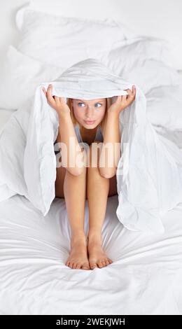 Bett, Decke und Frau verstecken sich morgens mit Angst oder Angst zu Hause und Laken, um den Körper zu bedecken. Nervös, Mädchen und Bettdecke über dem Kopf einer Person, die Angst hat Stockfoto