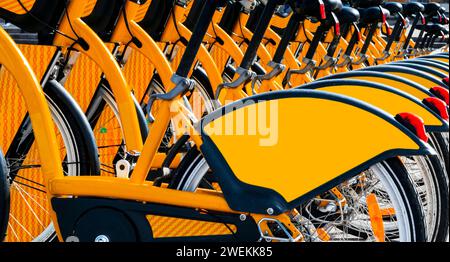 Eine Reihe geparkter Fahrräder. Reihe von geparkten bunten Fahrrädern. Leihfahrräder. Muster von Oldtimer-Fahrrädern, die auf dem Bürgersteig gemietet werden können. Stockfoto