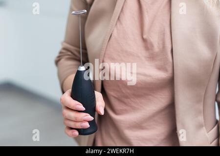 Die Hand hält einen Cappuccino-Mixer. Nahaufnahme. Isoliert auf weißem Hintergrund. Stockfoto
