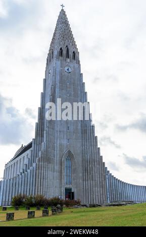 Niedriger Winkel der hohen lutherischen Pfarrkirche Hallgrimskirkja mit großer Baustruktur und Stufenbetonfassade auf grünem Grund in Reykjavik I. Stockfoto