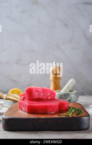 Niedriger Winkel des rohen Ahi-Thunfischsteaks auf dem Schneidebrett mit Gewürzen Stockfoto