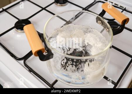Blick von oben auf einen transparenten Glastopf mit kochenden Eiern auf einem Gasherd Stockfoto