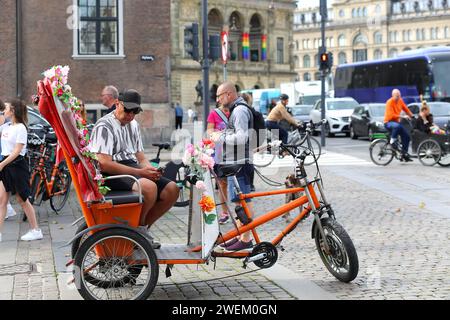 Kopenhagen, Dänemark - 17. August 2023: Der Nyhavn-Kanal: Radfahrer in der Altstadt. Mann sitzt auf Schubkarren-Lastenfahrrad. Bewegung i Stockfoto