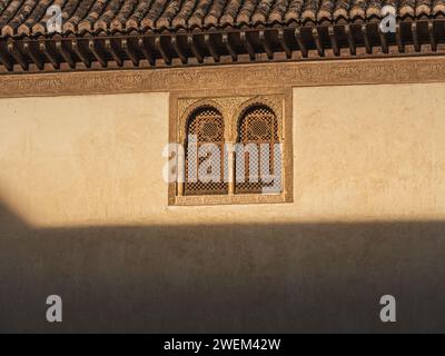 Sonnenlicht an einer Wand und ein graviertes Fenster eines berühmten arabischen Palastes der Alhambra in Andalusien, das Licht und Schatten auf die gravierten Wände wirft Stockfoto