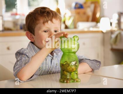 Junge, Münzen in eine Spardose in Form eines Teddybären Stockfoto