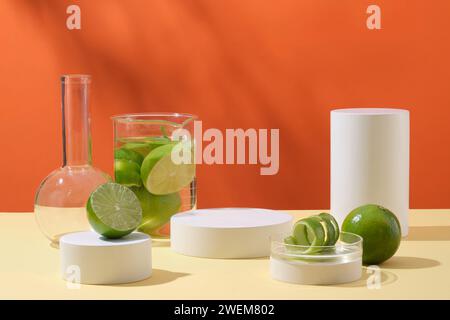 Laborglaswaren mit frischen Limetten und weißen leeren Podesten, die auf orangefarbenem Hintergrund mit Schattenblättern verziert sind. Werbeszene für Kosmetik Stockfoto