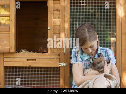 Süßes Mädchen, das braunes Kaninchen hält Stockfoto