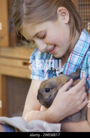 Süßes Mädchen, das braunes Kaninchen hält Stockfoto