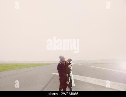 Paar auf der Landebahn des Flughafens umarmen Stockfoto