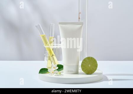 Szene für Werbekosmetik von Kalkextrakt mit Plastikflasche unbeschriftet, Kalkhälften und Laborglas gefüllt mit gelber Flüssigkeit auf weißem Hintergrund Stockfoto