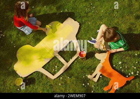 Kinder malen Karton Cut Outs im Garten Stockfoto