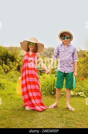 Jungen und Mädchen, die mit Stroh Hut und Sonnenbrille Lächeln Stockfoto