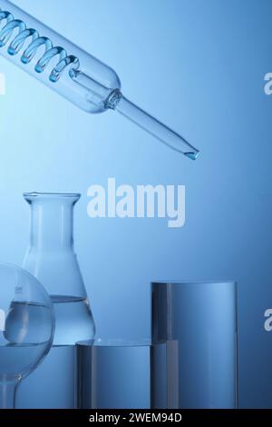 Vorderansicht der mit Laborgeräten gefüllten transparenten Lösung und Zylinderpodien auf blauem Hintergrund. Leeres Feld für die Produktpräsentation. Wissenschaft Stockfoto