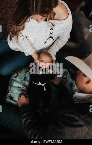 Mom und Dad wechseln das Outfit des Jungen auf der Couch Stockfoto