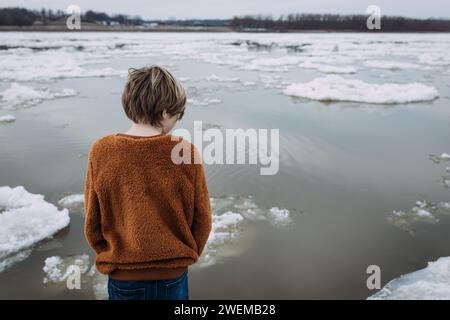 Kind, das auf das Eis schaut, das den Mississippi River hinunter schwimmt Stockfoto