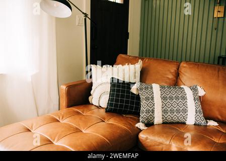 Braune Ledercouch im Wohnzimmer neben dem Fenster Stockfoto