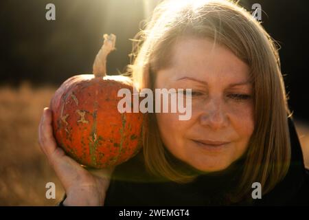 Portrait von Frau mit Kürbis mitten in einem Maisfeld Stockfoto