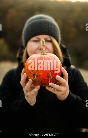Portrait von Frau mit Kürbis mitten in einem Maisfeld Stockfoto
