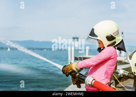 Kleines Mädchen, das sich als Feuerwehrmann ausgibt, Tag der offenen Tür in der Feuerwache. Zukunftsberuf für Kinder. Bildungsprogramm für Schulkinder Stockfoto