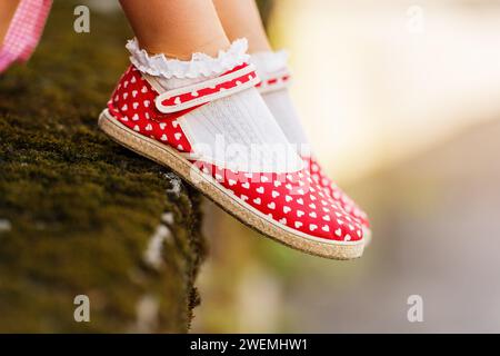 Nahaufnahme von roten Pünktchenschuhen an Kinderfüßen Stockfoto