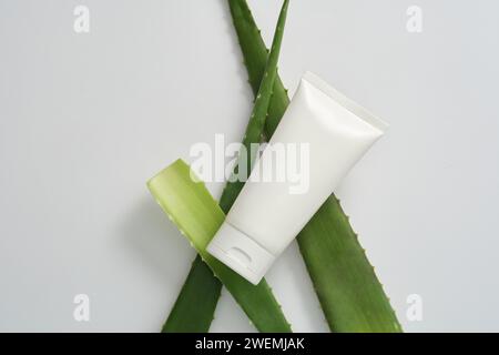 Regenerierende und feuchtigkeitsspendende Kosmetik mit natürlichem Aloe-Extrakt für Gesichtspflege auf weißem Hintergrund mit frischen Aloe Vera Blättern. Mockup-Szene mit W Stockfoto