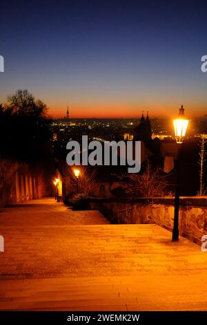 Blick von der Burg in Prag, Blick hinunter auf die Stufen, die von den Lampenpfählen mit Sonnenaufgang beleuchtet werden Stockfoto